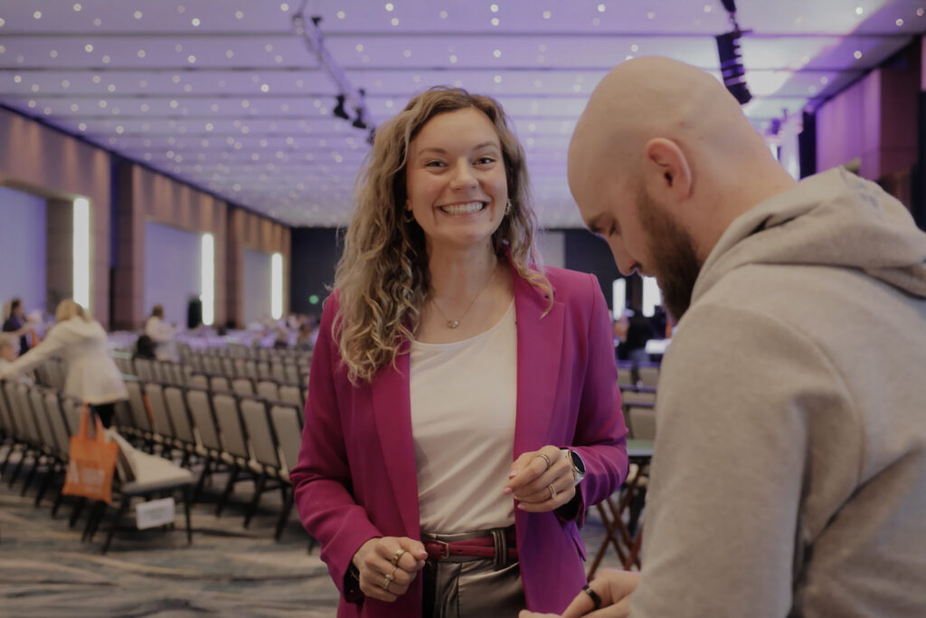 Rachel Eslick smiling backstage with a crew member before stepping on stage to deliver her keynote.