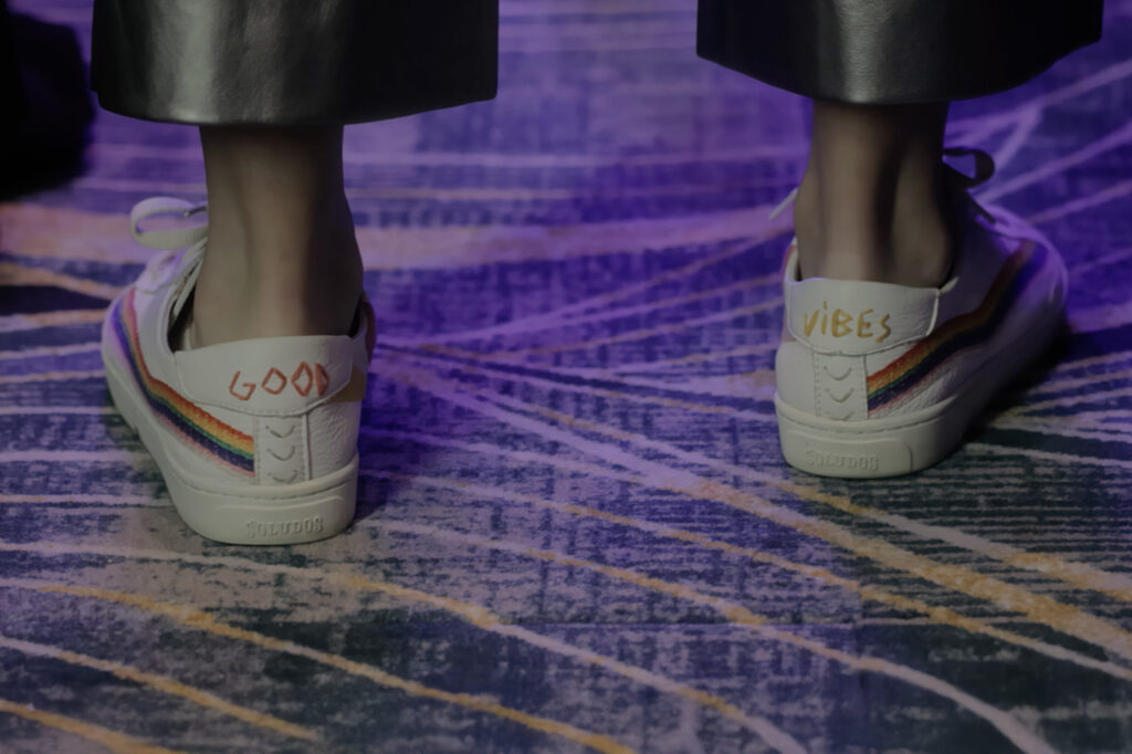 Close-up of Rachel Eslick’s sneakers with “Good Vibes” written on the heels as she stands on stage.